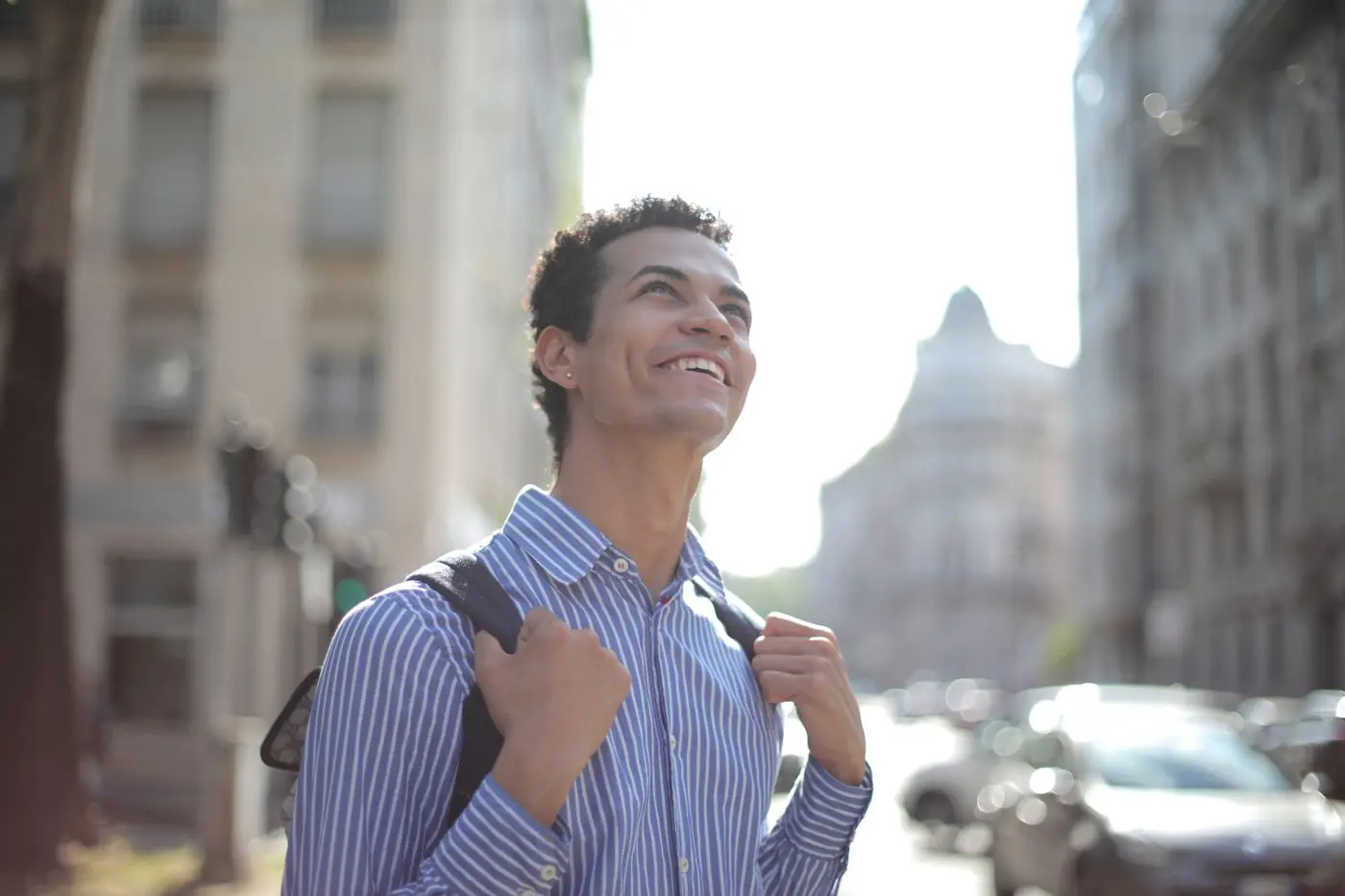 A smiling man in a striped shirt on a city street
